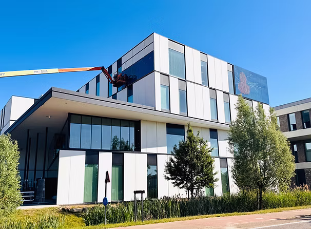 Nuhma headquarters Herkenrodesingel Hasselt — ISSOL® Fresco full-colour BIPV panels displaying The Flying Duckman artwork by Nele Bijnens, 2025